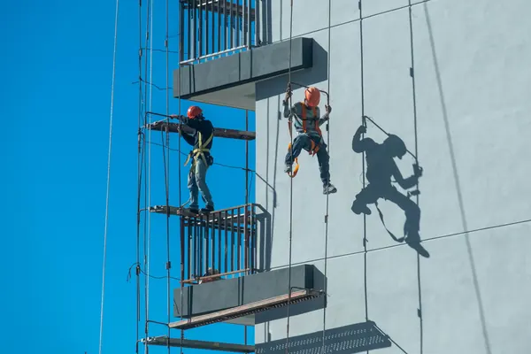 Alpiniści pracują przy balkonach na elewacji budynku