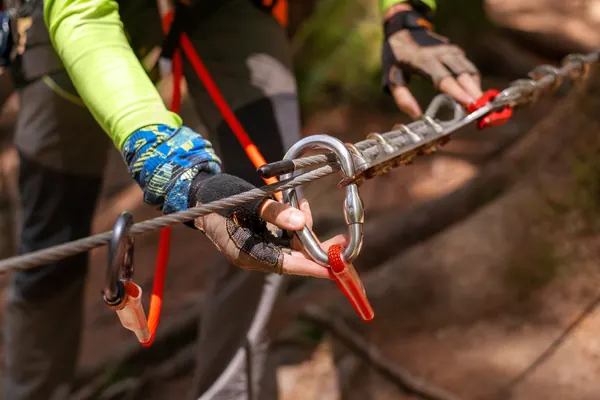 Karabinki i lina stalowa w dłoniach alpinisty