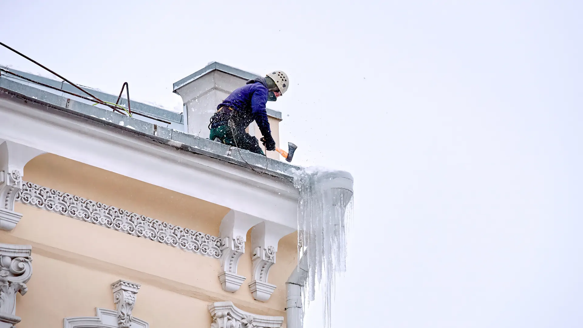Alpinista usuwa sople z gzymsu kamienicy